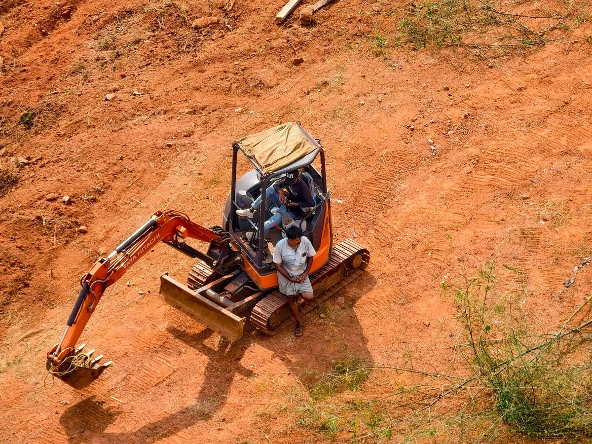 Imagen de referencia: excavadora sobre terreno de tierra rojiza (fotografía de archivo, no es una obra de Constructora G2)